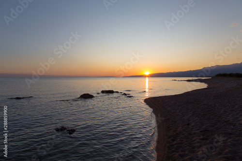 Beautiful sunset on a lake in the mountains. Kyrgyzstan  Issyk-Kul Lake. Bright sky  background in warm colors.