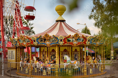 Children's carousel with horses. Bright summer photo of a children's attraction. Photo taken on a sunny summer day. City attraction for young children.