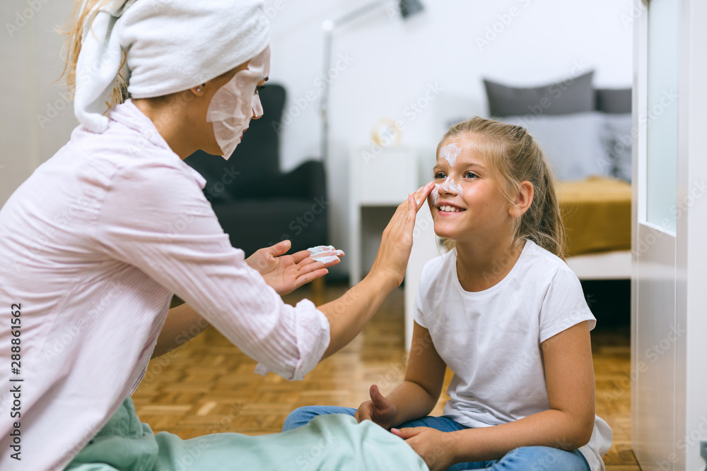 mother and daughter applying cosmetic face mask at home mother and daughter applying cosmetic face mask at home