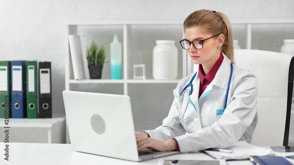 Focused young beautiful female doctor working using laptop pc at modern clinic Focused young beautiful female doctor working using laptop pc at modern clinic