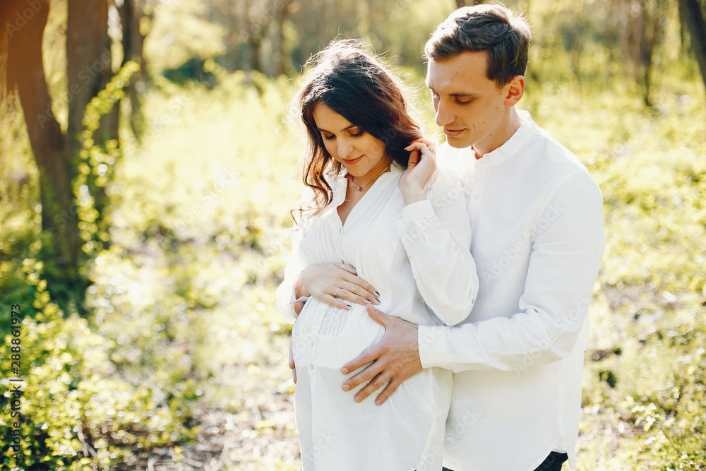 bright and happy pregnant woman walking in the park with her husband bright and happy pregnant woman walking in the park with her husband