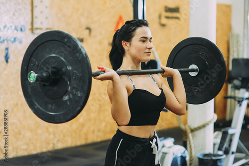 young strong girl is engaged with a barbell in the gym