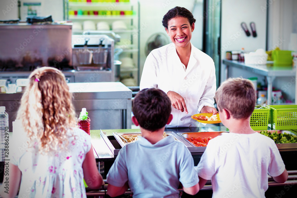 Cheerful woman serving food to schoolchildren Cheerful woman serving food to schoolchildren