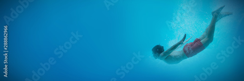 Tablou pe pânză Young man swimming underwater
