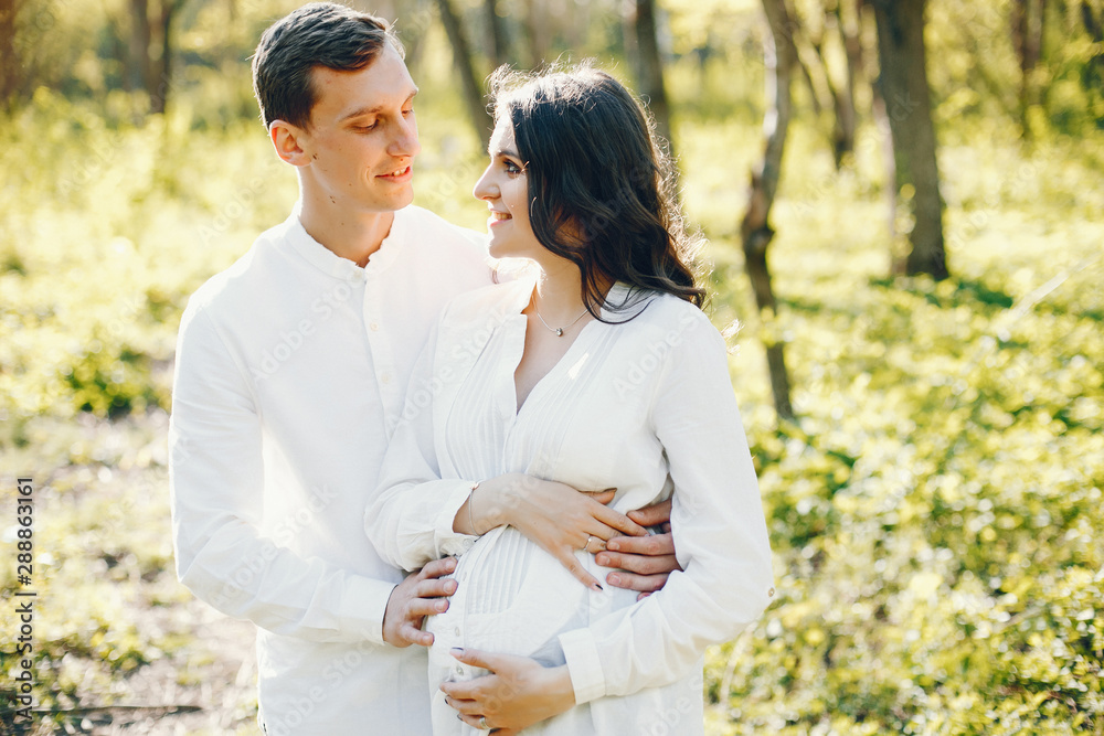 bright and happy pregnant woman walking in the park with her husband bright and happy pregnant woman walking in the park with her husband