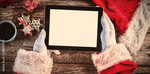 Santa claus holding digital tablet on wooden plank