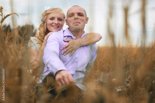 Just married lovers walking in a field in autumn day