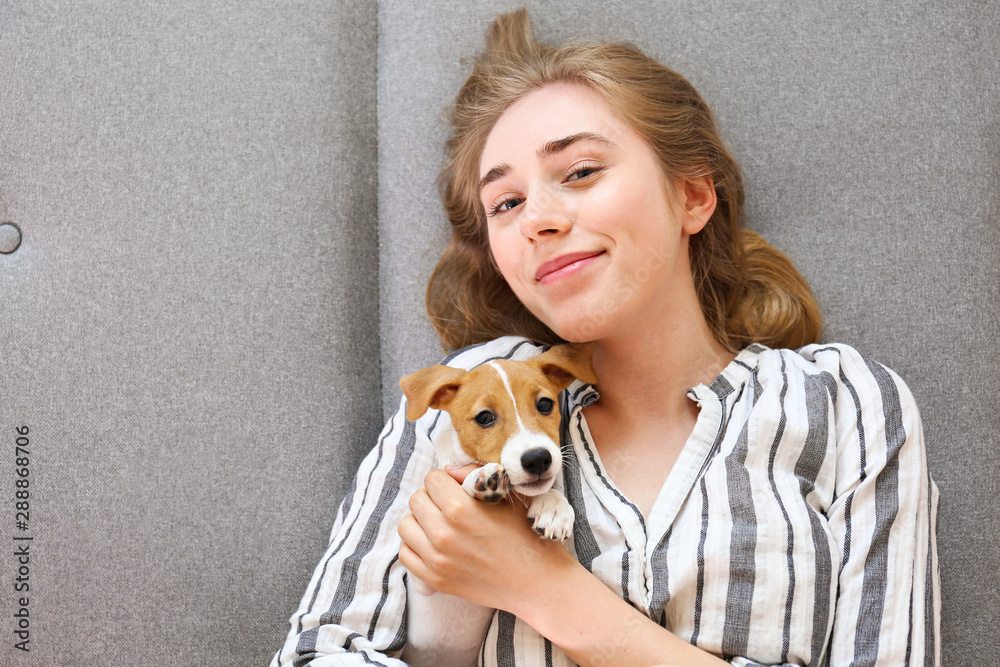 The cutest two months old Jack Russel terrier puppy with beautiful blonde young woman. Small adorable doggy with funny fur stains lying with owner. Close up, copy space, isolated background. The cutest two months old Jack Russel terrier puppy with beautiful blonde young woman. Small adorable doggy with funny fur stains lying with owner. Close up, copy space, isolated background.