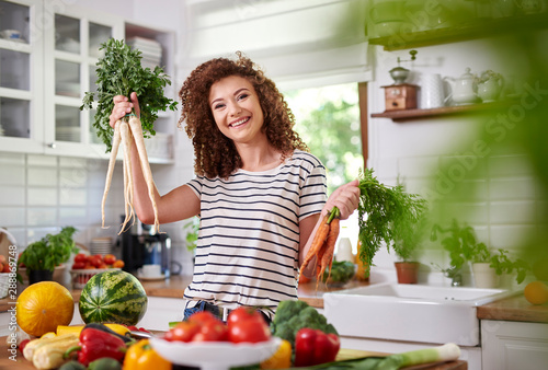Young woman holding a bunch of organic carrots and parsley