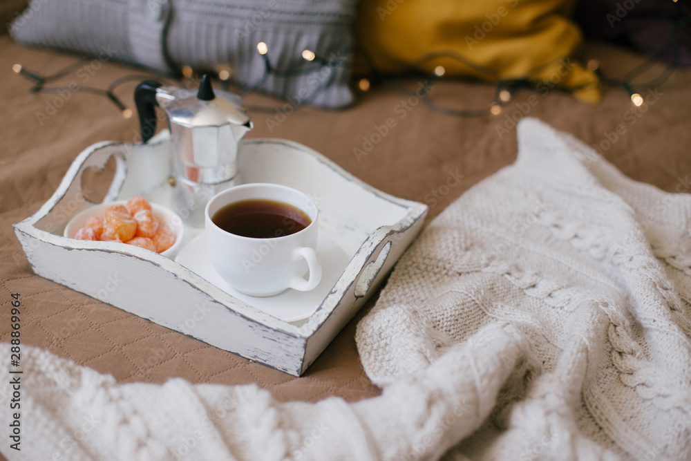 Wooden tray with coffee and kumquat on bed in cozy room. Wooden tray with coffee and kumquat on bed in cozy room.