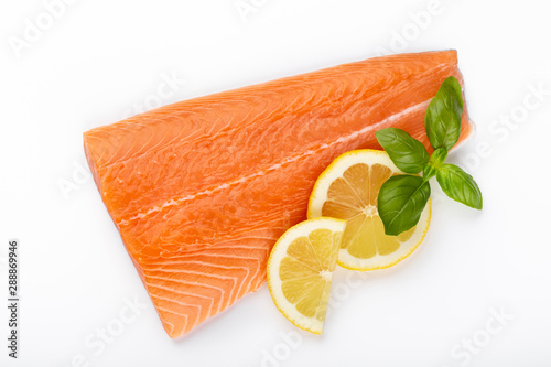 Fresh raw salmon fillets with herbs and lemon isolated on white background.