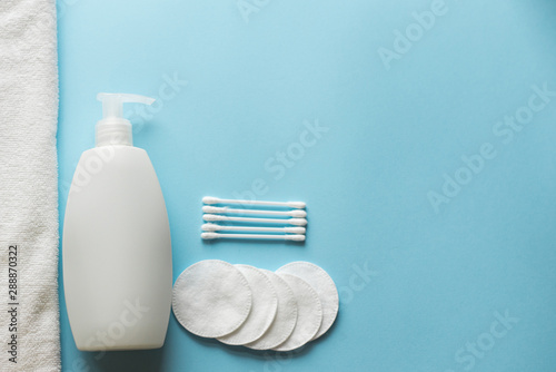 cotton pads, soap bottle and towel on blue background , copy space, template. skincare products