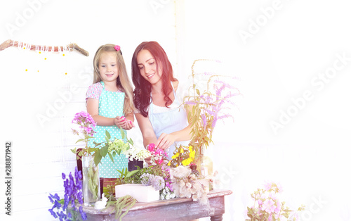 A young girl with a daughter is picking up a bouquet. A young mother with her daughter makes a flower. Summer house in the village by the garden. Rest in the village.