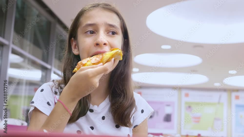 Close-up. face teen girl eating pizza in a fast food restaurant.