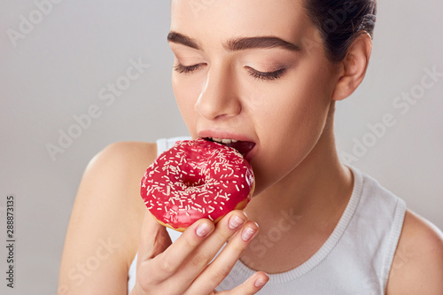 Young Woman Eating Donut. Brunette Girl Tastes a Donut. Sweets Are Unhealthy Junk Food. Dieting  Healthy Eating  Lifestyle. Weight Loss
