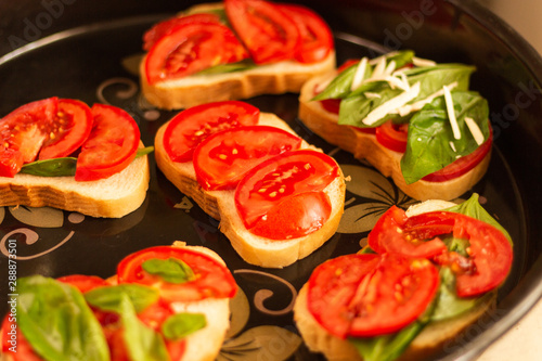 making sandwiches with tomato and basil on a baking sheet for the oven