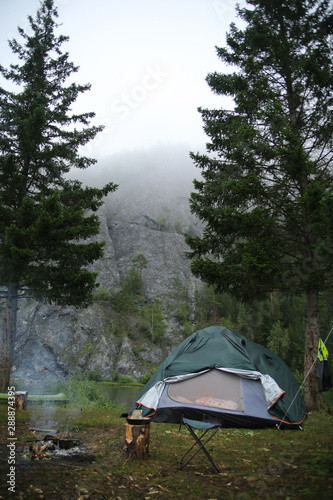 tent on the bank of the river against the background of rocks in the fog