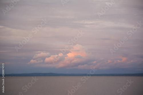 Volumetric pink and blue clouds at sunset over the water