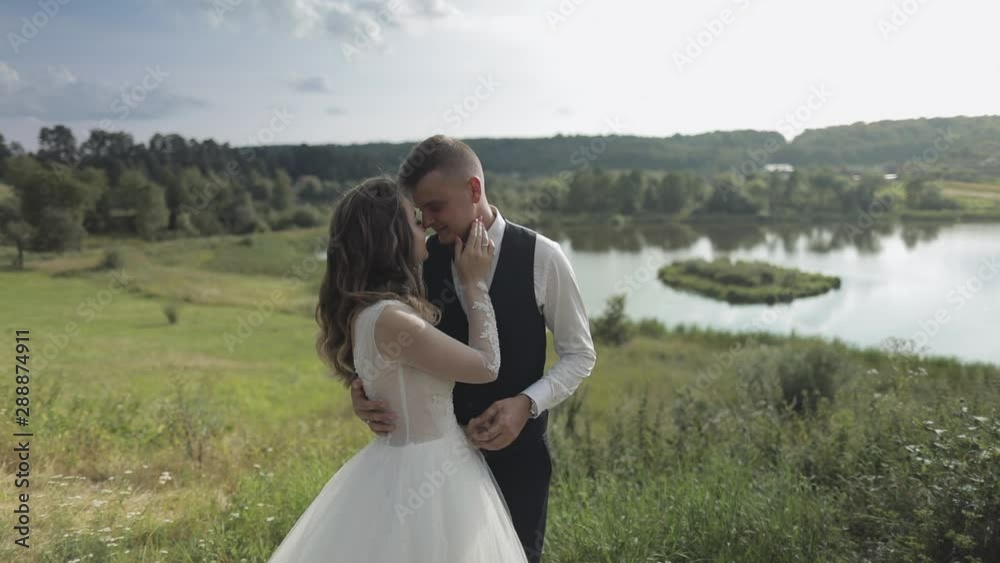 Caucasian groom with bride in the park near lake. Wedding couple. Newlyweds kiss Caucasian groom with bride in the park near lake. Wedding couple. Newlyweds kiss