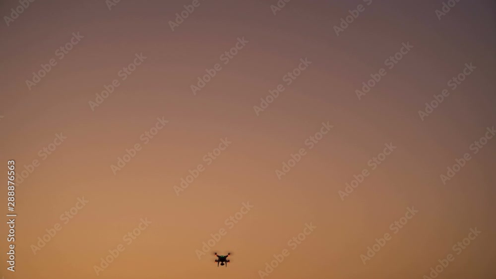 Drone silhouette flying in the sky. Beautiful sky colors at sunset Drone silhouette flying in the sky. Beautiful sky colors at sunset