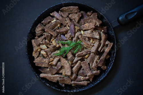 Cooked liver on frying pan on the black background