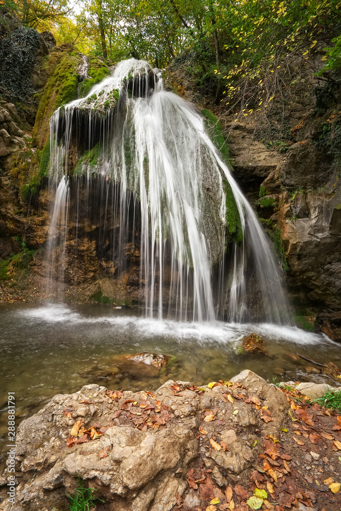 Obraz premium Beautiful waterfall at mountain river in colorful autumn forest. Nature landscape