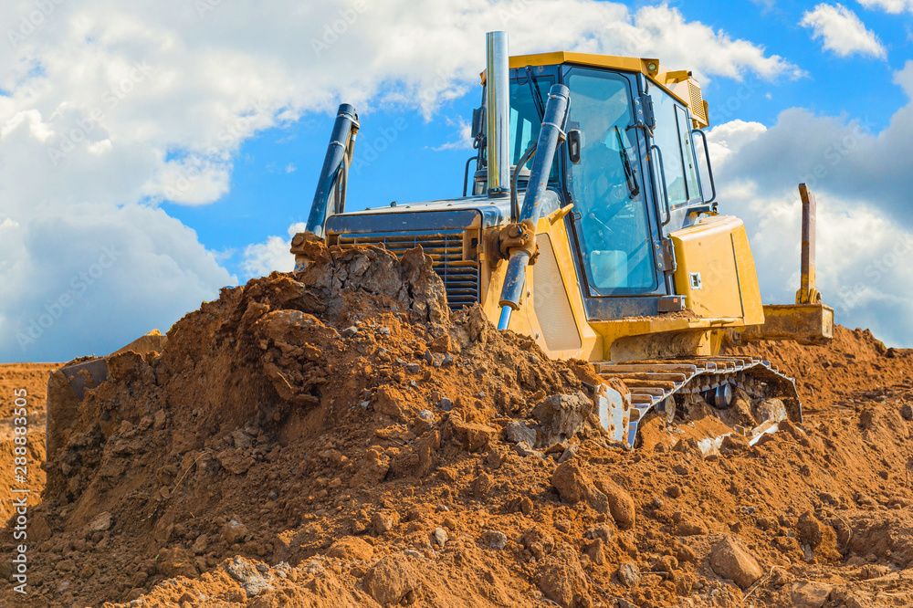 Crawler bulldozer - excavator with clipping path on a background with blue sky and clouds. work on construction site or sand pit