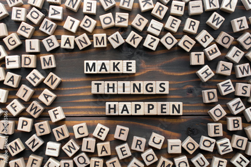 make things happen - phrase from wooden blocks with letters, keep it simple motivational concept, random letters around, white  background