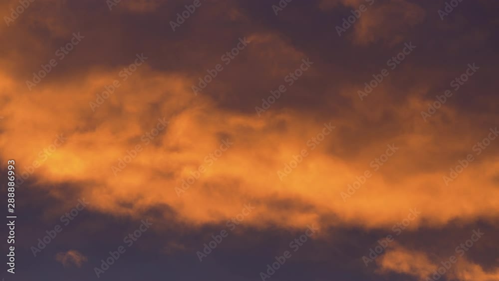 Golden clouds illuminated by disappearing rays at sunset floating across dramatic dark violet and purple thunderclouds in sky to change summer weather. Stunning view natural meteorology background. Golden clouds illuminated by disappearing rays at sunset floating across dramatic dark violet and purple thunderclouds in sky to change summer weather. Stunning view natural meteorology background.