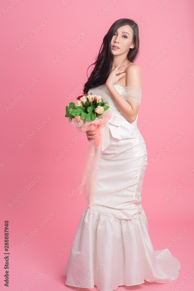 Portrait of bride wearing a bridal dress on the pink. Asian model in white dress in studio.