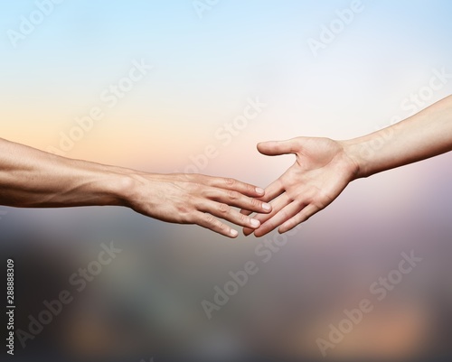 Hands of man and woman reaching to each other on blurred background © BillionPhotos.com