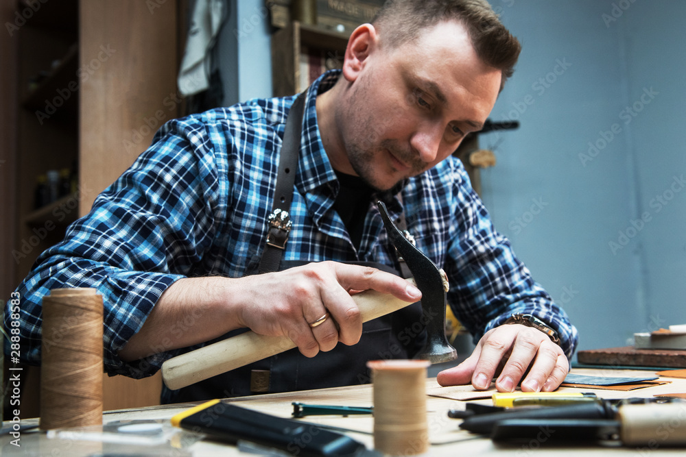 Man working with leather textile at a workshop. Concept of handmade craft production of leather goods. Man working with leather textile at a workshop. Concept of handmade craft production of leather goods.