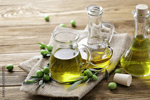 olive oil and fresh green olives on wooden background