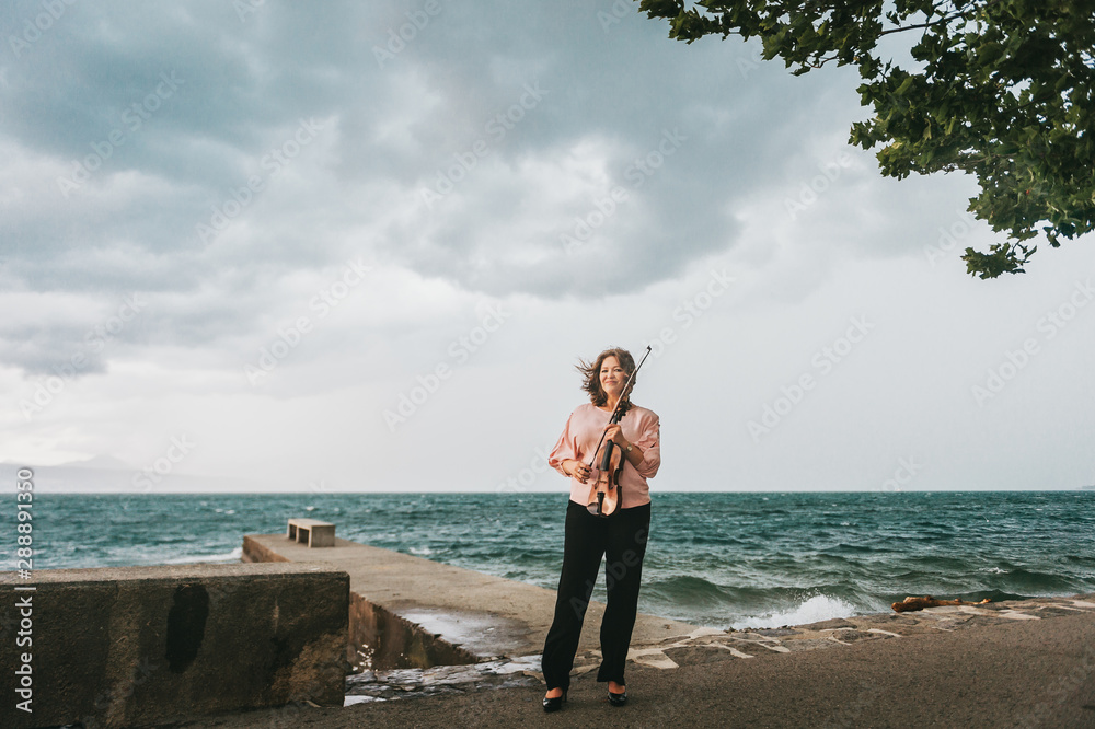 Outdoor portrait of beautiful woman with violin, dark rainy day Outdoor portrait of beautiful woman with violin, dark rainy day