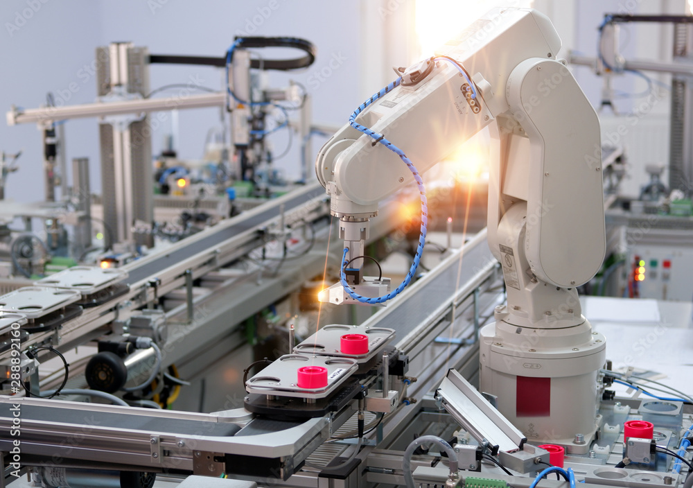 Focus on robotic arm's gripper. Industry 4.0 concept; artificial intelligence in smart factory. Robot picks up the product from automated car on the manufacturing line. Selective focus. Focus on robotic arm's gripper. Industry 4.0 concept; artificial intelligence in smart factory. Robot picks up the product from automated car on the manufacturing line. Selective focus.