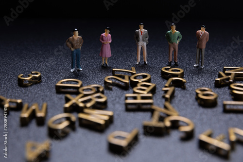 Miniature people: Group of small businessmen looking alphabet.