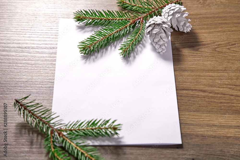 Fototapeta premium empty paper with fir branches and cones on the wooden background