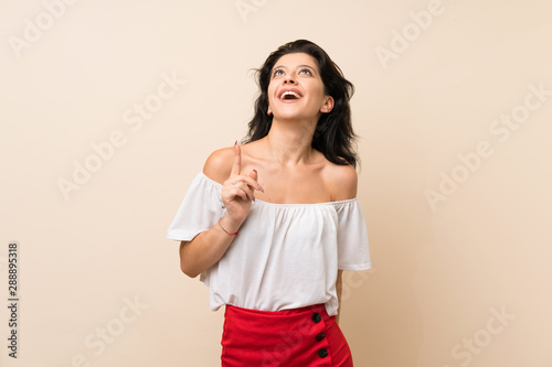 Young woman over isolated background pointing up and surprised