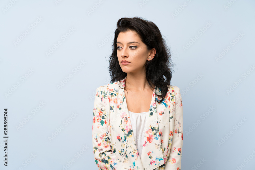 Young woman over isolated blue background looking side Young woman over isolated blue background looking side