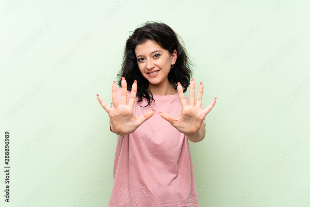 Young woman over isolated green background counting ten with fingers Young woman over isolated green background counting ten with fingers