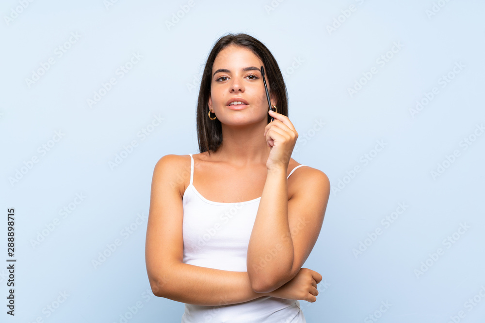 Young girl holding makeup brush over isolated background Young girl holding makeup brush over isolated background