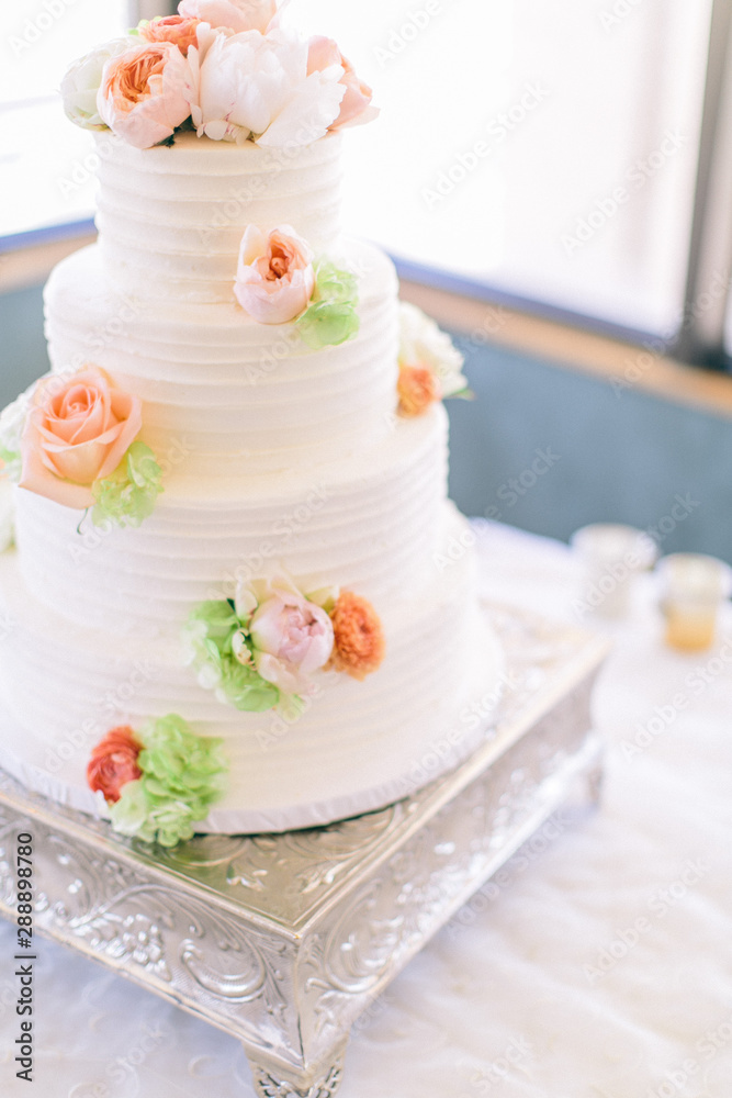 Fine white wedding cake decorated with pink and orange peony flowers, copy space