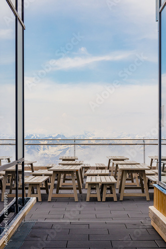 Outdoor wooden tables of a restaurant at the top of Zugspitze mountain in the European Alps on a summer day © Gaschwald