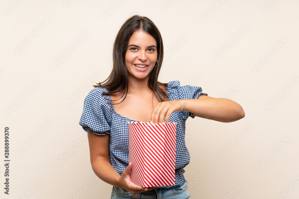 Young girl over isolated background holding a bowl of popcorns Young girl over isolated background holding a bowl of popcorns