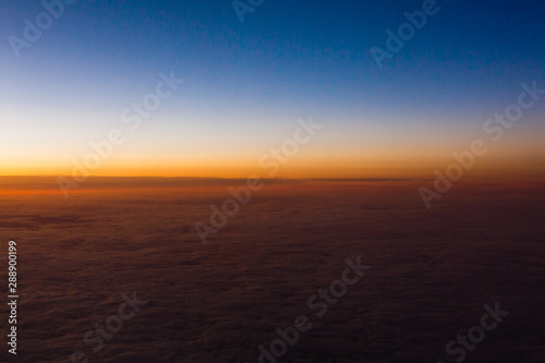Beautiful sunset sky above clouds with dramatic light. Cabin view from airplane