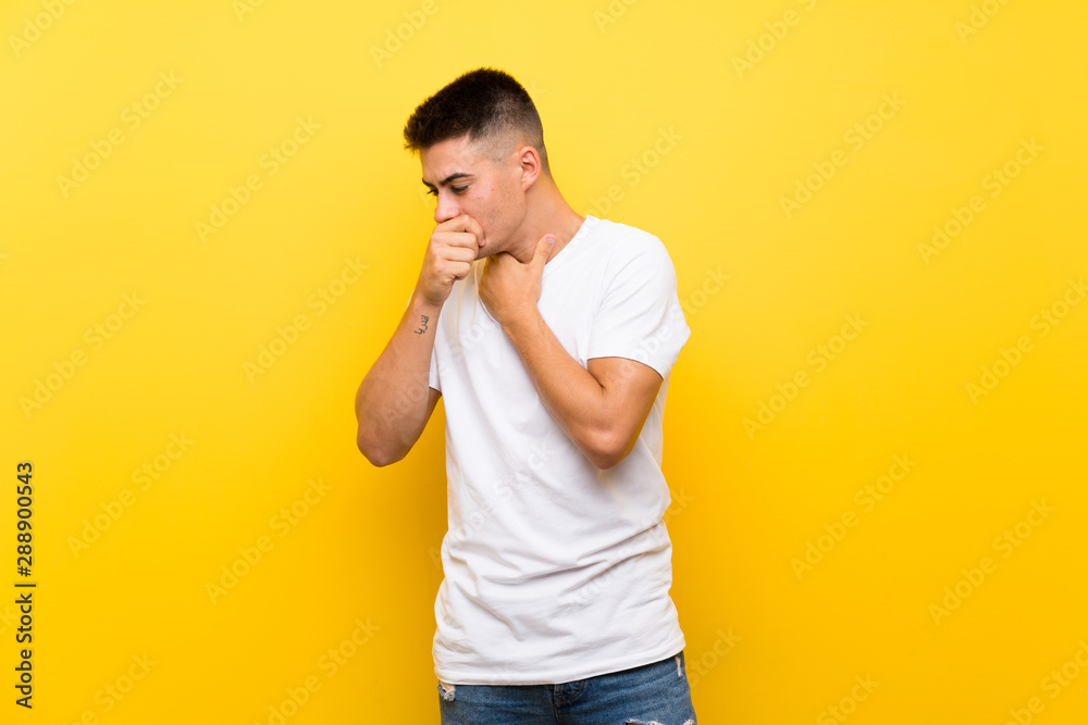 Young handsome man over isolated yellow background is suffering with cough and feeling bad Young handsome man over isolated yellow background is suffering with cough and feeling bad