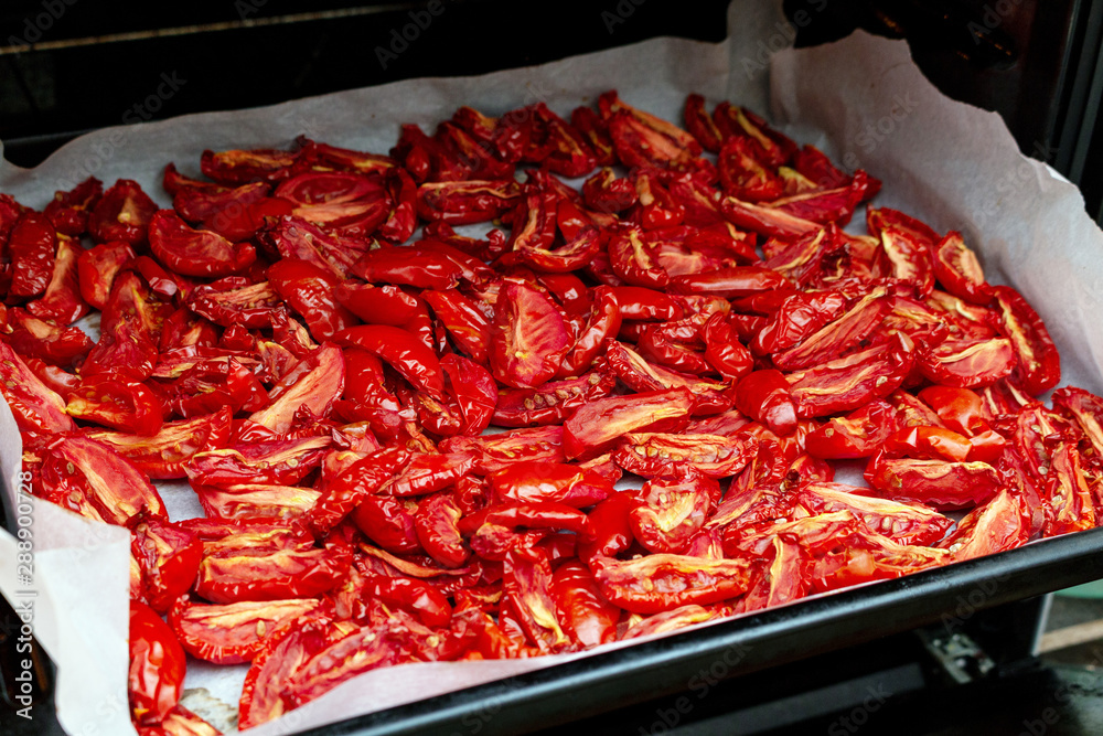 Homemade dried red tomatoes slices with basil oregano spices cooking process. Traditional Italian Mediterranean kitchen cuisine. Homemade dried red tomatoes slices with basil oregano spices cooking process. Traditional Italian Mediterranean kitchen cuisine.