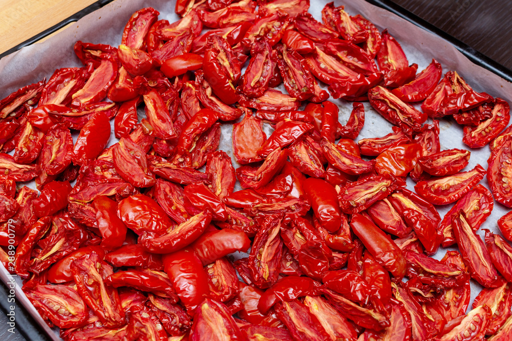 Homemade dried red tomatoes slices with basil oregano spices cooking process. Traditional Italian Mediterranean kitchen cuisine. Homemade dried red tomatoes slices with basil oregano spices cooking process. Traditional Italian Mediterranean kitchen cuisine.