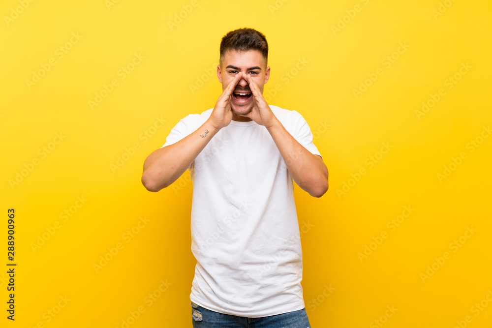 Young handsome man over isolated yellow background shouting and announcing something Young handsome man over isolated yellow background shouting and announcing something