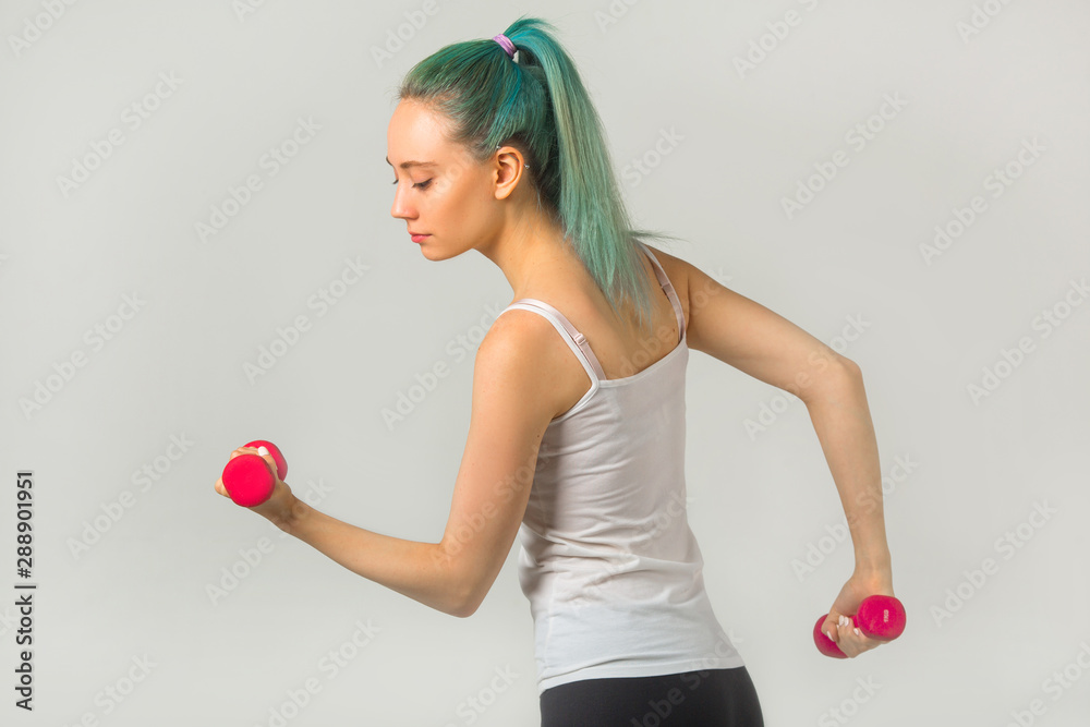 beautiful young woman in sportswear goes in for sports with dumbbells beautiful young woman in sportswear goes in for sports with dumbbells